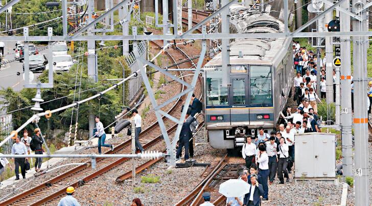地震發生後鐵路癱 瘓，一眾上班族下車沿 路軌離開。 法新社